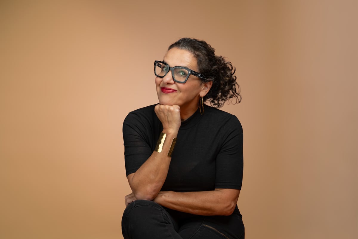 Cindy Friedman in a black turtleneck, resting her chin on her hand